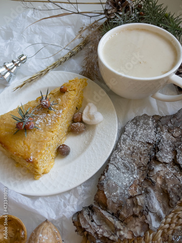 Cup of latte coffee and piece of apple pie on a decorated holiday table