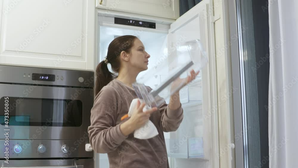 New modern white kitchen, woman cleaning empty integrated refrigerator built into kitchen housing. High quality 4k footage New modern white kitchen, woman cleaning empty integrated refrigerator built into kitchen housing. High quality 4k footage