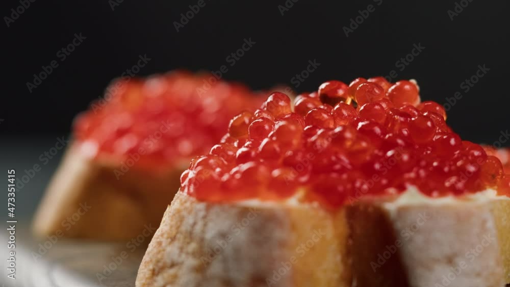 Red caviar sandwiches close-up. Bread with salmon salted orange roe on black background. Raw seafood. Luxury delicacy food. Delicious and tasty fish products. Russian cuisine. Festive dinner, Red caviar sandwiches close-up. Bread with salmon salted orange roe on black background. Raw seafood. Luxury delicacy food. Delicious and tasty fish products. Russian cuisine. Festive dinner,