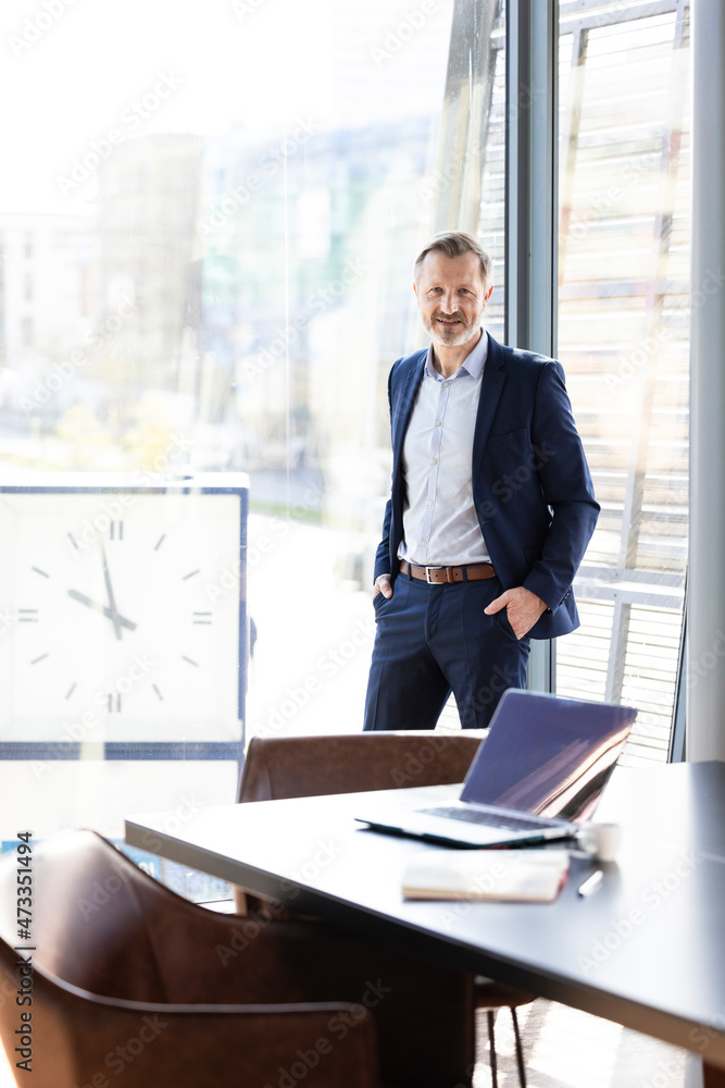 Businessman with hands in pockets standing in office Businessman with hands in pockets standing in office