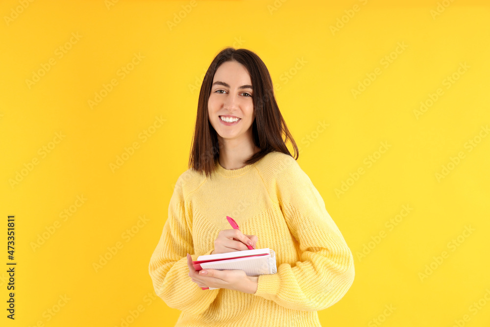 Fototapeta premium Attractive girl with notebook on yellow background
