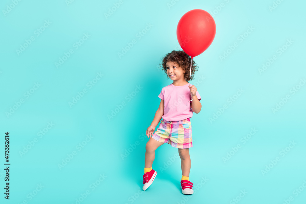 Full length photo of young little hispanic girl happy positive smile hold air balloons isolated over turquoise color background Full length photo of young little hispanic girl happy positive smile hold air balloons isolated over turquoise color background
