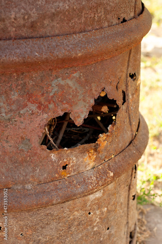 a hole in an old rusty metal barrel