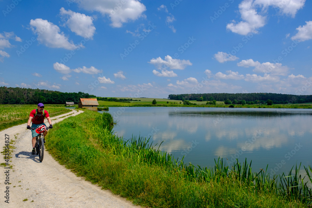 Germany, Franconia, Uehlfeld, Mature man cycling along carp pond Germany, Franconia, Uehlfeld, Mature man cycling along carp pond