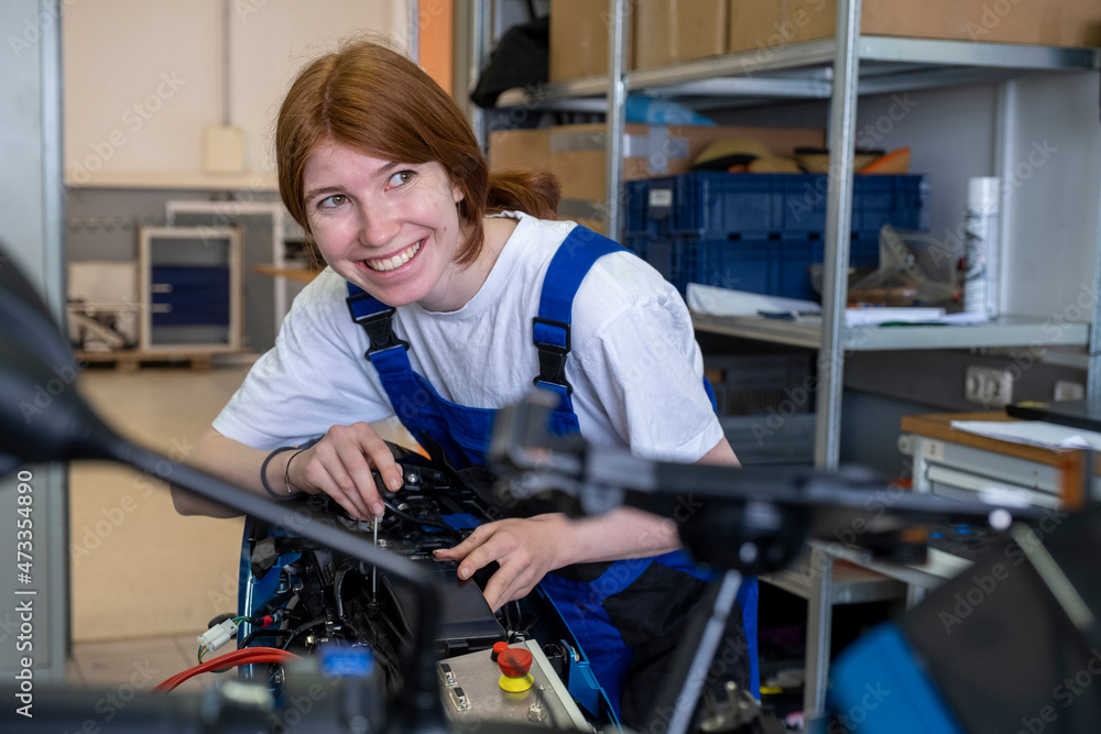 Smiling female technician looking away while working at workshop
