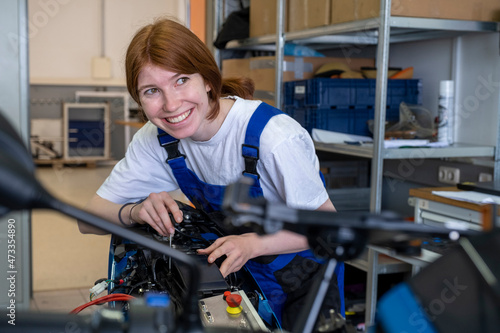 Smiling female technician looking away while working at workshop photo