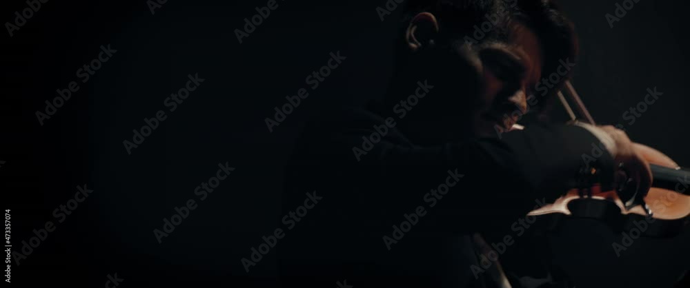 CU Portrait of young aspiring musician playing violin on a stage of a large venue. Shot with 2x anamorphic lens
