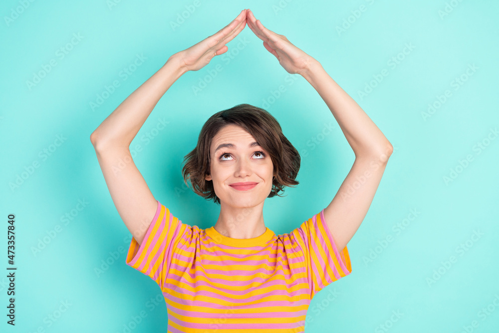 Photo of charming cute young lady wear orange t-shirt smiling looking showing arms roof isolated turquoise color background Photo of charming cute young lady wear orange t-shirt smiling looking showing arms roof isolated turquoise color background