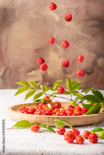 Pitangas falling on a wooden plate on a white plastic tablecloth on the table  selective focus.