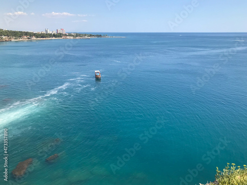 A fishing boat sails along a calm river or sea. Top view