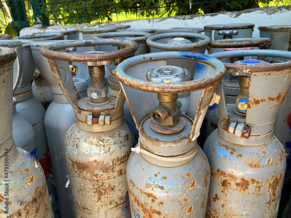 Many various older portable gas cylinders in front of gas store for service
