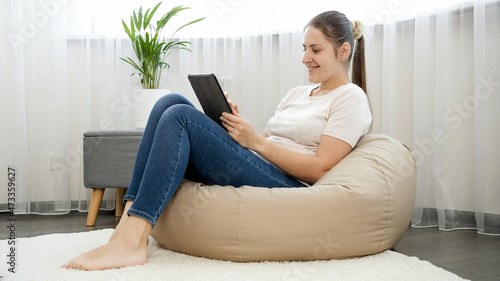 Smiling freelance girl sitting at home office and working on tablet computer