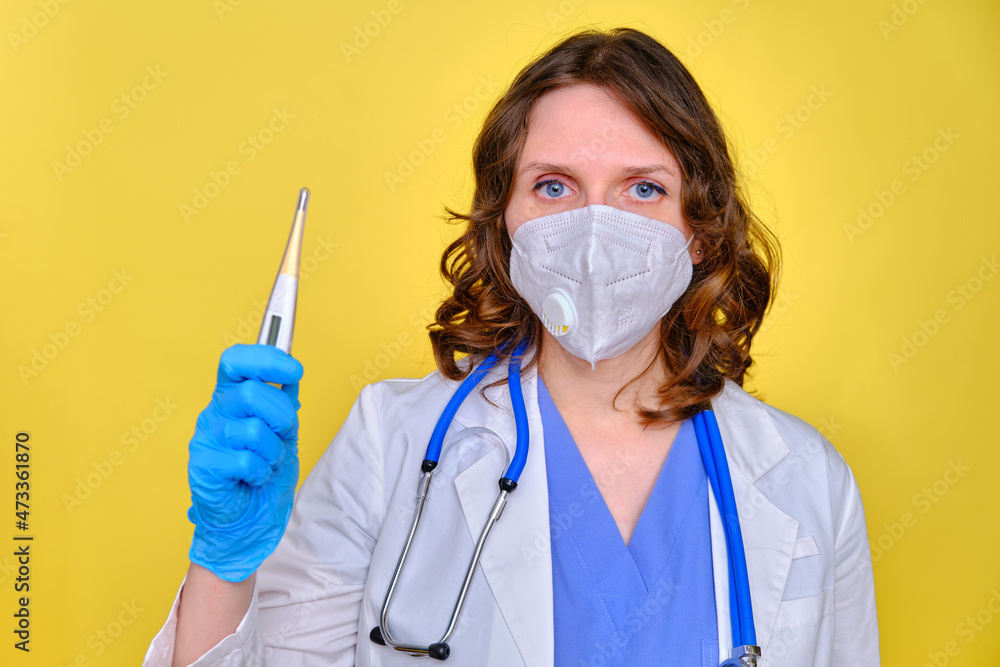 Doctor in a white uniform with a electronic thermometer in his hand on a yellow background Doctor in a white uniform with a electronic thermometer in his hand on a yellow background