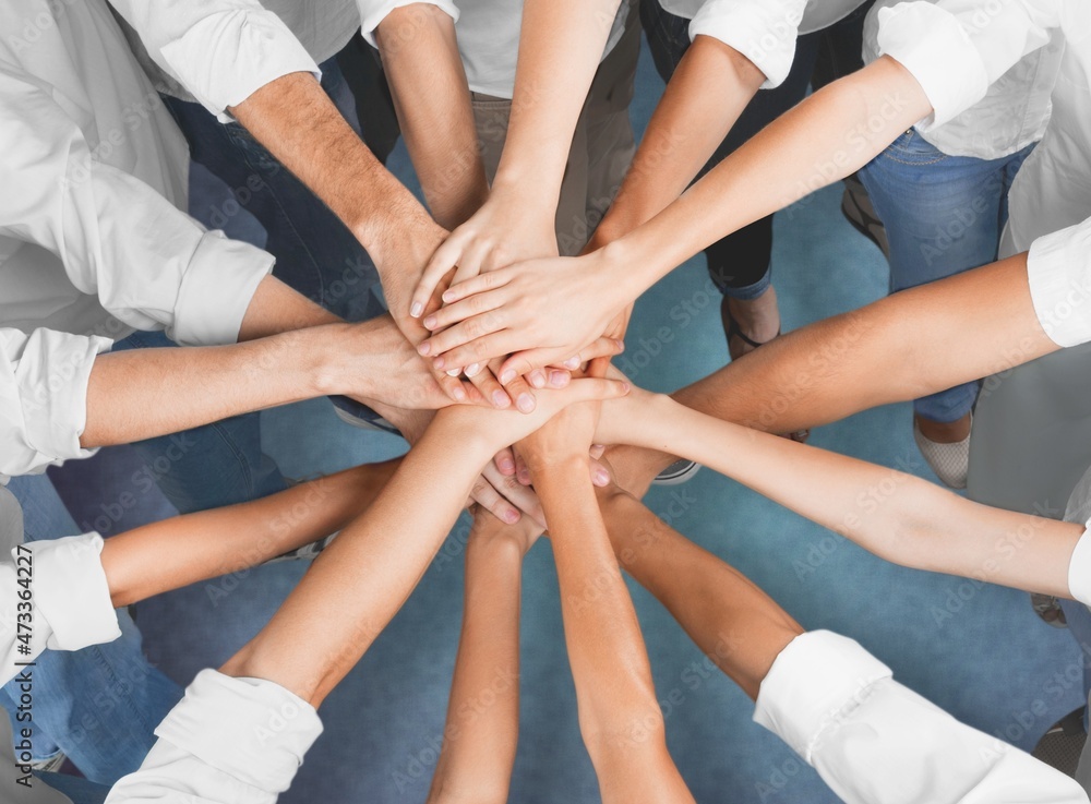 Teamwork And Unity Concept. A young diverse group of people put hands together Teamwork And Unity Concept. A young diverse group of people put hands together