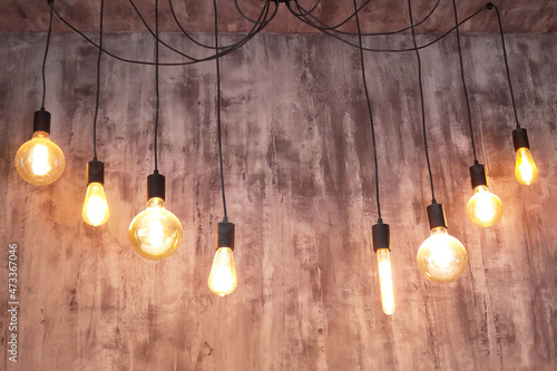 Edison type incandescent lamps on gray wall background, lamp soft yellow glow in loft style
