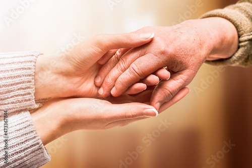 young hand holds hand of senior, care and help concept