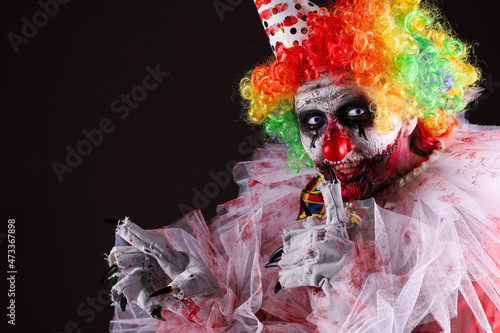Fototapeta Naklejka Na Ścianę i Meble -  Terrifying clown on black background, space for text. Halloween party costume