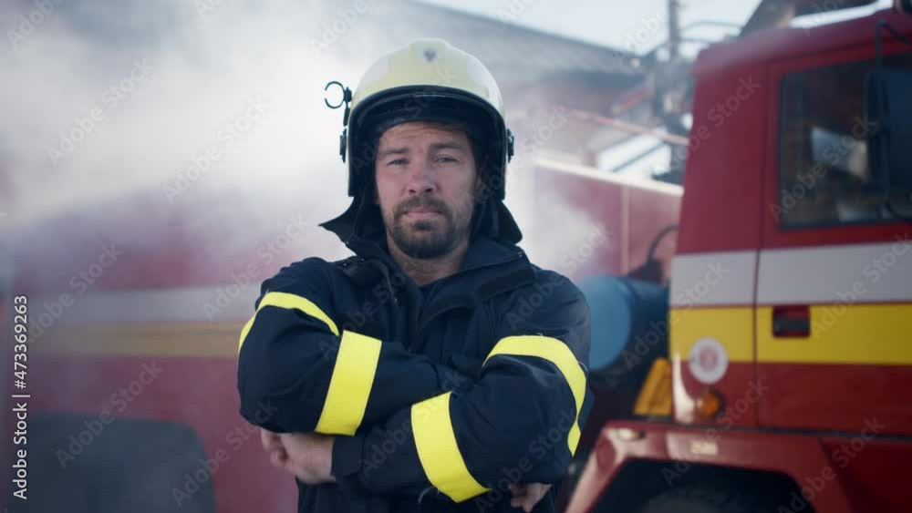 Mature dirty firefighter putting on helmet with fire truck at background Mature dirty firefighter putting on helmet with fire truck at background