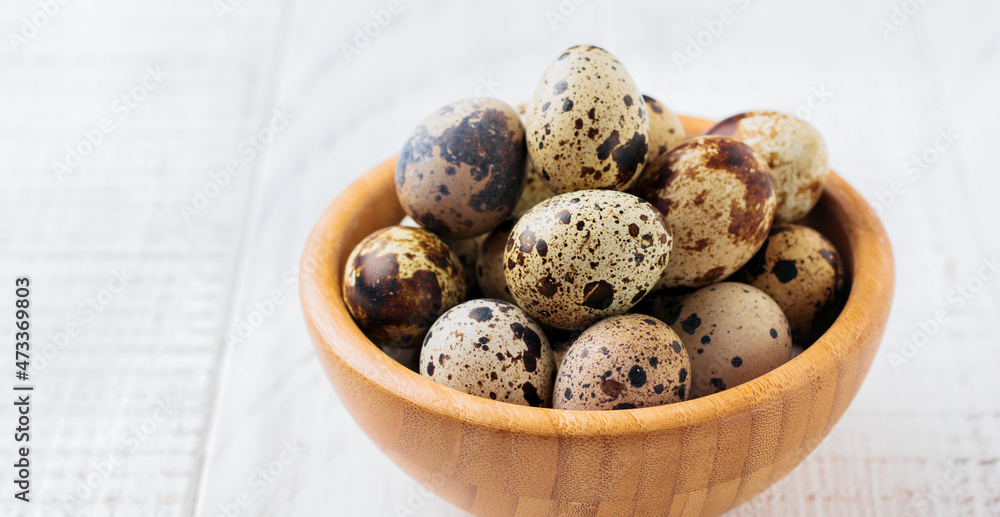 Obraz premium Quail eggs in metal plate on white wooden old background. Selective focus.