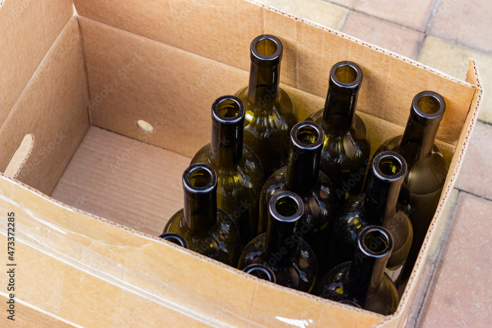Empty olive-colored wine bottles packed in a box and prepared for bottling