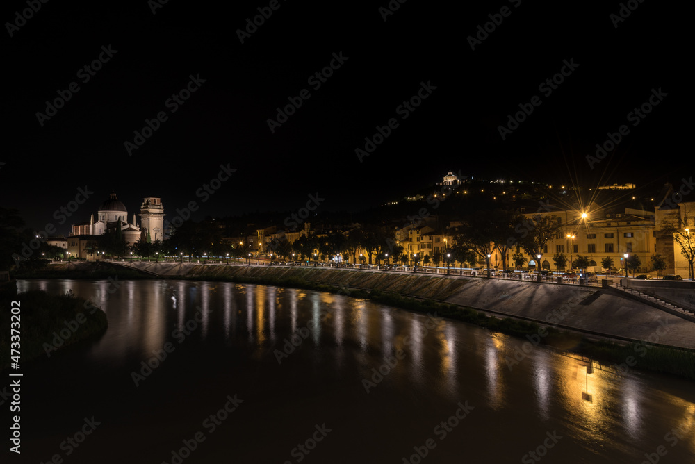 City landscape with the illuminated streets along the bank of the Adige river at night, Verona, Veneto Region, Italy