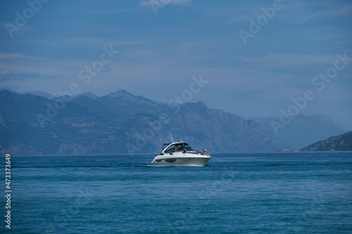 A large white boat is moving slowly on blue water. White yacht on a mountain lake against the backdrop of mountains top view.