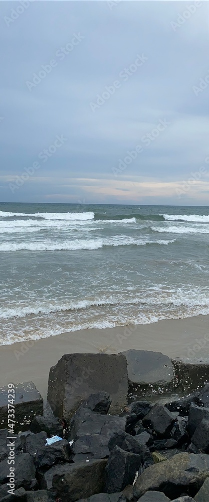 waves crashing the sandy beach. clear horizon. changing windy weather, sunset seascape with rocky beach and crashing waves