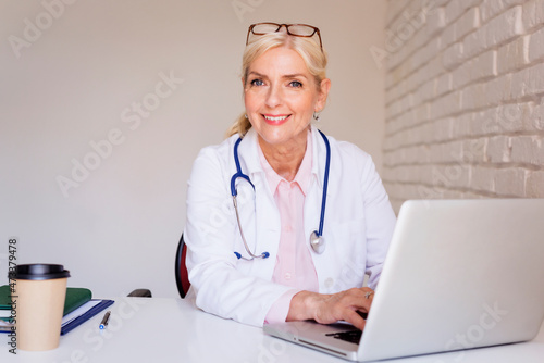 Smiling female doctor working on laptop at the doctor's office