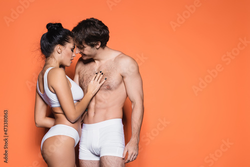 sexy couple in white underwear standing isolated on orange.