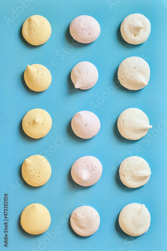 Colored fruit meringues lying in rows on a blue background