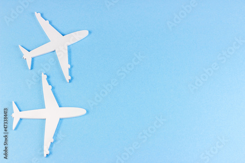 Top view flat lay of white plane models on light sky blue background with copy space.