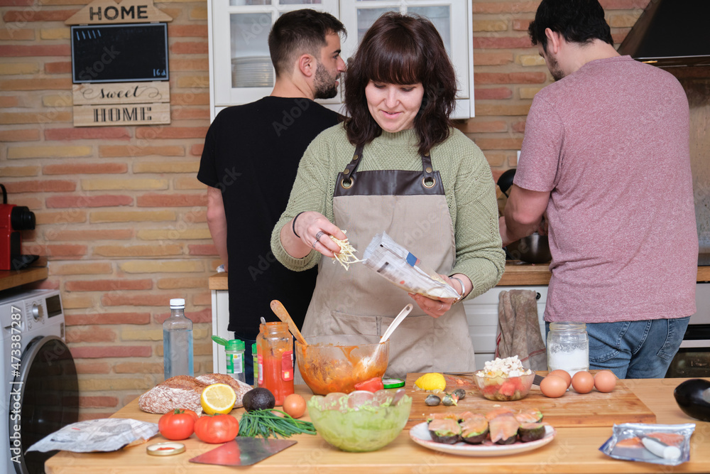 Group of three friends smiling, talking and cooking. Group of three friends smiling, talking and cooking.