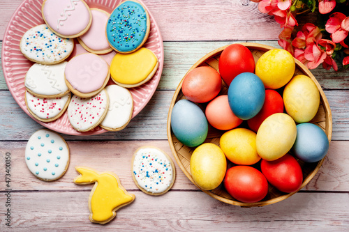 Easter cookies and colorful eggs on pink wooden background