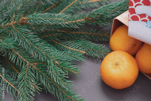 Winter background with Christmas tree branches, cones, Christmas toys, cookies and tangerines, with black space for replicas