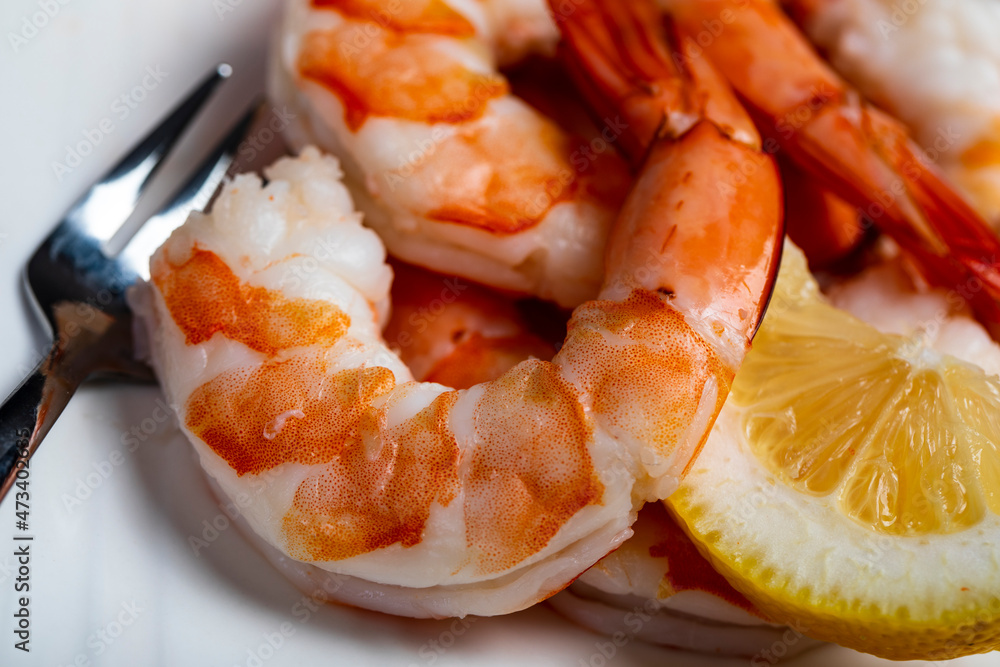 Close up of fresh shrimp on a plate with forks and lemon slice Close up of fresh shrimp on a plate with forks and lemon slice