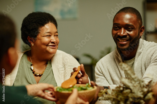 Portrait of happy African-American family chatting cheerfully while enjoying dinner together