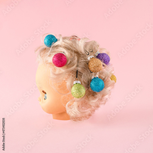 Creative concept of New Year's hairstyle on pink  background. The doll's hair is decorated with colorful balls. photo