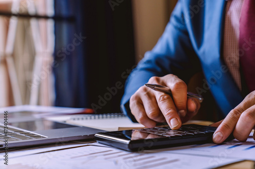 businessman working in the office with using a calculator to calculate the numbers finance accounting concept, Dedicated to the progress and growth of the company, Financial and tax systems concept.