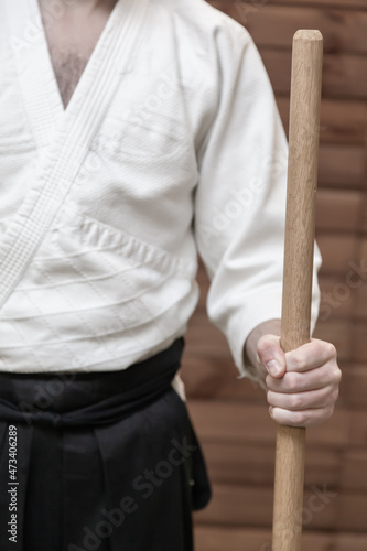 A man holds a wooden jo weapon in his hand
