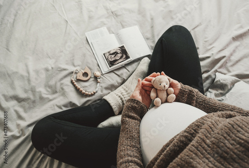 Woman pregnant belly with little teddy toy bear. Concept photo with symbol of many meanings for expectant mother during pregnancy and her unborn baby. photo
