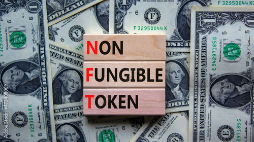 NFT non-fungible token symbol. Concept words NFT non-fungible token on wooden blocks. Beautiful background from dollar bills, copy space. Business and NFT non-fungible token concept.