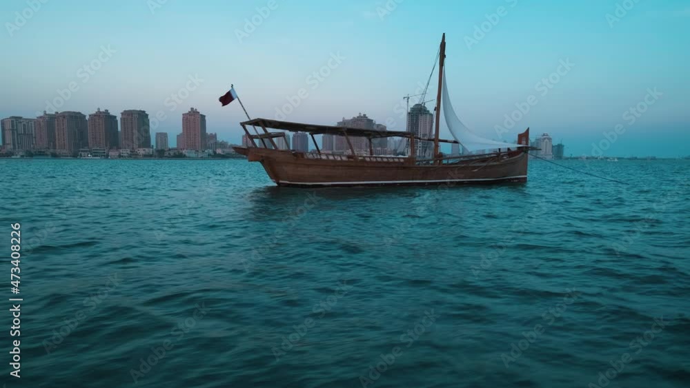 dhows with Qatar Flag in Arabic gulf and Katara skyline in background during Katara eleventh traditional dhow festival in Doha Qatar sunset shot from sailing boat dhows with Qatar Flag in Arabic gulf and Katara skyline in background during Katara eleventh traditional dhow festival in Doha Qatar sunset shot from sailing boat