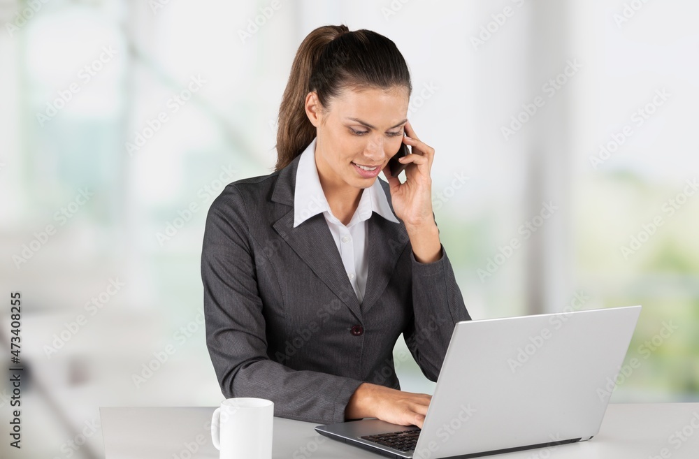 happy young worker with laptop speaking on a smartphone in modern beauty salon. happy young worker with laptop speaking on a smartphone in modern beauty salon.