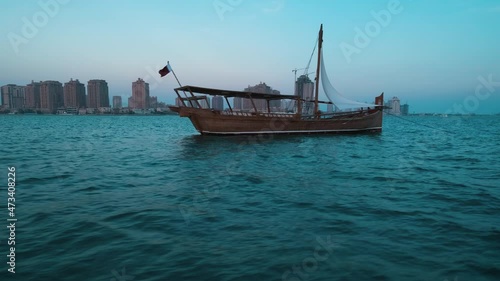  dhows with Qatar Flag in Arabic gulf and Katara skyline in background during Katara eleventh traditional dhow festival in Doha Qatar sunset shot from sailing boat 