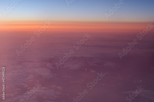 Early sunrise above clouds. Airplane view
