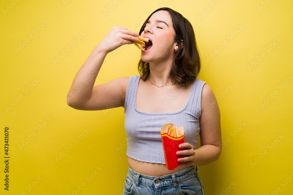 Beautiful hungry woman enjoying eating fries Beautiful hungry woman enjoying eating fries