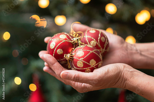 hands holding red balls to hang on a x-mas tree photo