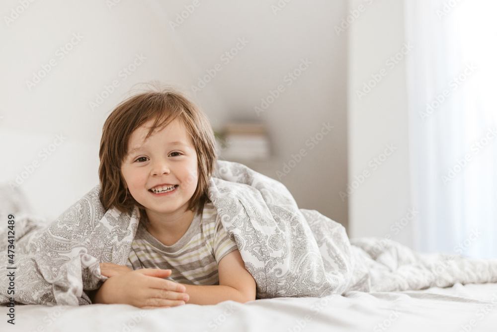 Cute boy, toddler is indulging in bed. Happy childhood. Games with parents during quarantine. Holidays at home. Cute boy, toddler is indulging in bed. Happy childhood. Games with parents during quarantine. Holidays at home.