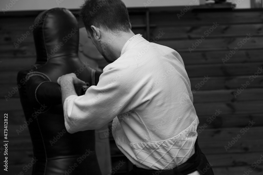 a man in a kimono and a hakama practicing blows on a sports dummy a man in a kimono and a hakama practicing blows on a sports dummy