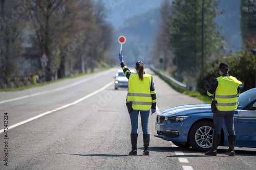 Italian Police controls on the road. Officers with masks and gloves monitor passing motorists. Street control for the Covid-19 with a policewoman. Police checkpoint. photo
